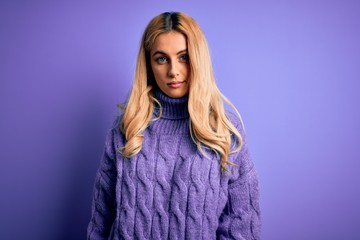 Young beautiful blonde woman wearing casual turtleneck sweater over purple background looking sleepy and tired, exhausted for fatigue and hangover, lazy eyes in the morning.