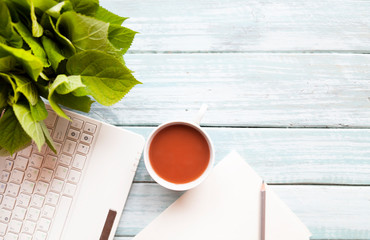 White office desk with smartphone with blank screen mockup, laptop computer, cup of coffee and supplies. Top view with copy space, flat lay.