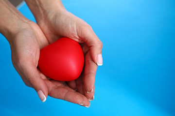 Close-up of persons hands holding red heart. Symbol of affection and love. Copy space in right side. Cardiology and medicine. Family relationship and adoption concept