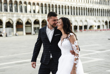 Naklejka premium happy bride and groom cuddle during a wedding walk,lovely couple's wedding day,beautiful outfits of the newlyweds,
