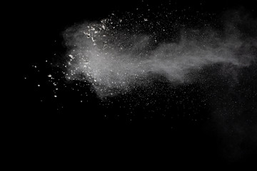 Freeze motion of white dust particles splash on black background.White powder explosion clouds.