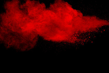 Red particles explosion on black background. Freeze motion of red dust splash.