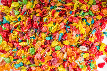Fototapeta na wymiar Colorful fruit cereal flakes. Multicolored fruit breakfast corn flakes, with various fruit taste, with milk and fresh berries on white table. Traditional american morning snack