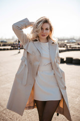 Gorgeous fashionable blondie woman with curly hair wearing in stylish coat and hat posing outdoors.Female fashion concept