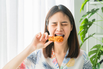 Happy young Asian woman holding fried chicken for eat.