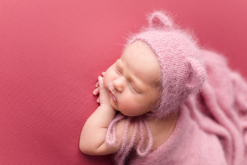 a newborn girl in a hat with ears. first photo session. newborn child. newborn.  the baby is lying on a pink blanket. newborn girl