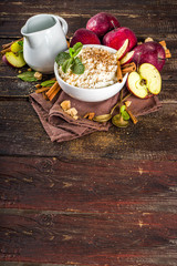Hot autumn breakfast or lunch porridge or pudding with apple and spices. Rice porridge with cinnamon and red apples, on a wooden rustic background.