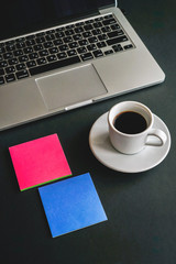 coffee laptop and stickers for notes on the table on a black background