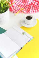 a coffee mug stands on a notebook, next to it lies a phone, pens 