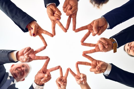 Group of business workers smiling happy and confident. Standing on a circle with smile on face doing symbol with fingers together at the office.
