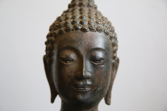 Budda, primo piano di testa in bronzo di provenienza tailandese, scultura su fondo bianco