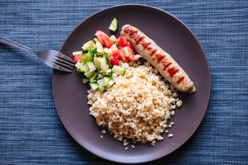 with pork sausage bulgur and tomato and cucumber salad. Close-up