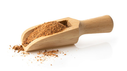 Nutmeg powder in wood scoop on white background