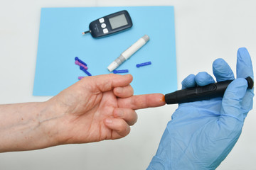Close up of woman hands using black  lancet on finger to check blood sugar level 