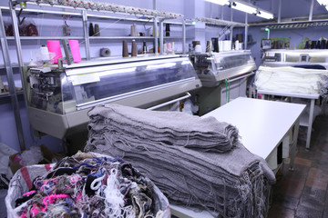 Pink spools of thread on the background of the sewing workshop. Clothing industry. Machine for the...