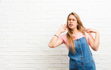 young blonde woman looking serious and curious, listening, trying to hear a secret conversation or...
