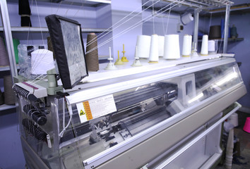 Pink spools of thread on the background of the sewing workshop. Clothing industry. Machine for the...