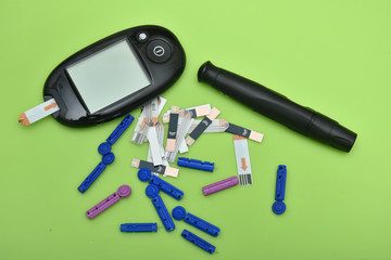 1 Diabetes set with glucometer, lancet, spare needles on green background 