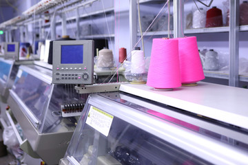 Pink spools of thread on the background of the sewing workshop. Clothing industry. Machine for the textile industry. Manufacture of wearing apparel. New factory for tailoring.