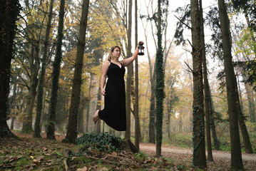 Woman with black dress holding lamp at park.