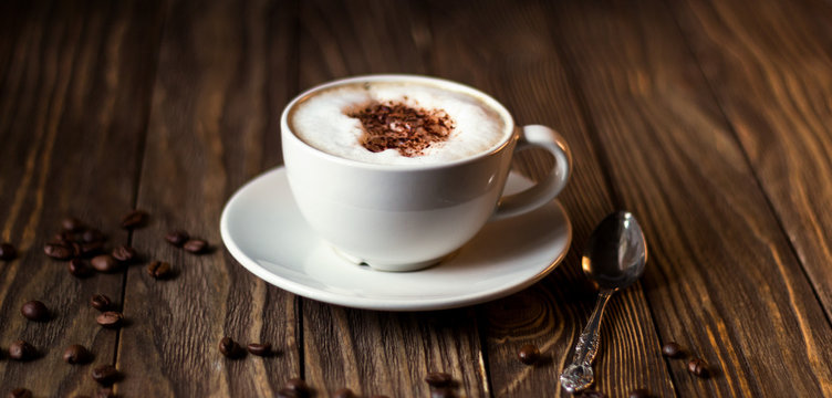 a Cup of coffee with milk and coffee beans on a dark wooden background. selective focus
