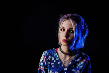 Infantile girl on a black background in blue light