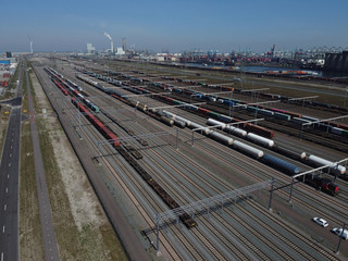 Fototapeta na wymiar Aerial bird view photo of railroad container terminal with train loaded with containers by overhead crane also showing classification yard and heavy industry