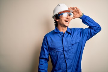 Young constructor man wearing uniform and security helmet over isolated white background very happy...