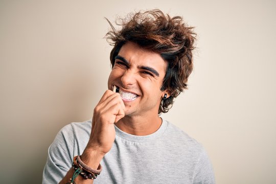 Young handsome man smiling happy. Standing with smile on face whasing tooth using toothbrush over isolated white background