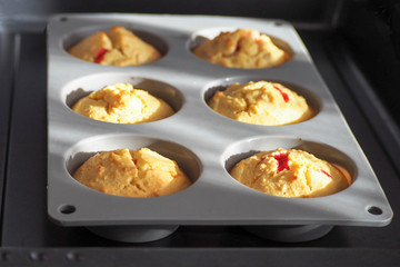 gluten-free muffins with red currant are prepared from the oven . . gray silicone mold for six pieces on a dark metal protwin