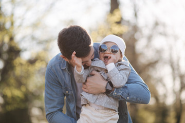 Fototapeta premium Happy cute daughter on father's hand. Dad and daughter walk in the park. Family mood. Little gil laugh