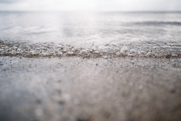 Close-up of waves on a stony beach, with small bubbles and ripples