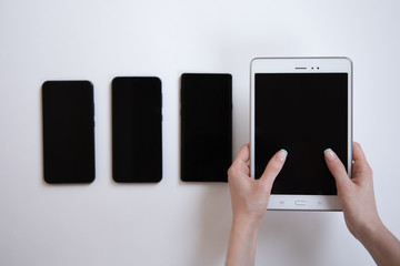 three phones are on a white background, and the tablet is in their hands
