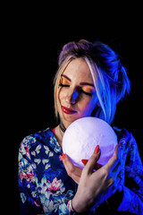 Infantile girl on a black background in blue light