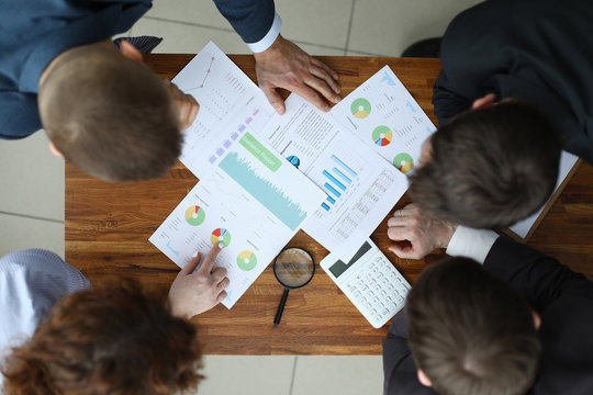 Top view of business team working on new project. Conference room with executive manager accountant and employee. Good deal and financial report. Papers with charts on wooden table