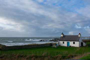 Fototapeta na wymiar A remote isolated, traditional, country cottage by a windswept beach on a winters day. A view out to the Irish sea from the Welsh island of Anglesey