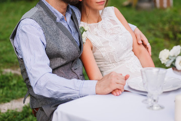 Wedding decoration table in the garden, floral arrangement for two people, In the style rustic. The bride & groom in summer outdoor. Woman and man embracing. Fine art family romantic.