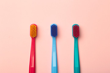 Toothbrushes of different colors on a pink background. Brushing teeth and oral hygiene.