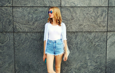 Beautiful young woman standing on city street over gray wall background