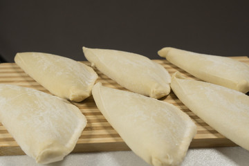 Cold chebureks with stuffing, on wooden blackboard.