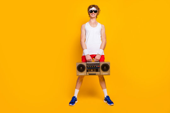 Full Length Body Size View Of Nice Funky Thin Cheerful Cheery Positive Glad Guy Holding In Hands Carrying Boombox Dj Party Isolated Over Bright Vivid Shine Vibrant Yellow Color Background