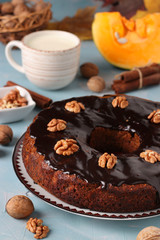 Homemade pumpkin muffin decorated with chocolate icing and cup of milk on a light blue background, Closeup, Vertical format