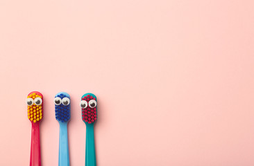 Kids toothbrushes of different colors on a pink background. Teeth and oral hygiene for children