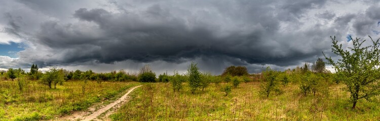Dramatic view of a shelf cloud over a field, horizontal cloud formation, panorama view.