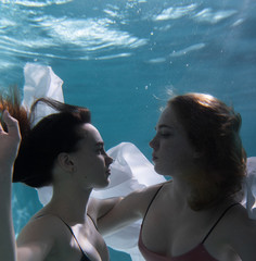 Two beautiful lesbian girls are swimming underwater. Attractiveness. Sexual poses and gestures....