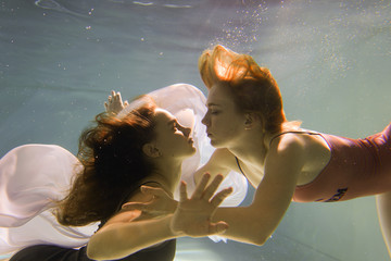 Two beautiful lesbian girls are swimming underwater. Attractiveness. Sexual poses and gestures....