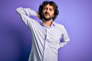 Young handsome business man with beard wearing shirt standing over purple background Suffering of neck ache injury, touching neck with hand, muscular pain