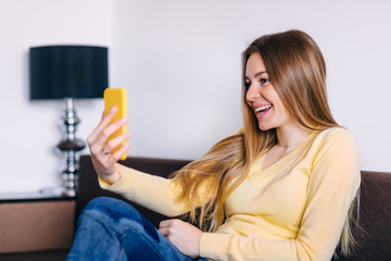 Portrait of happy female sit on cozy sofa in living room using m