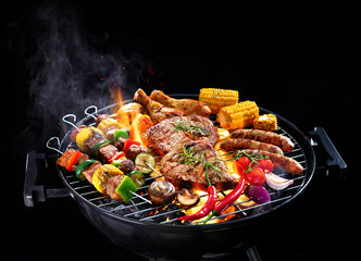 Assorted delicious grilled meat with vegetables on barbecue isolated on black background