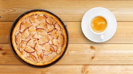 Homemade apple pie with cinnamon and cup of coffee on wooden table. Top view.